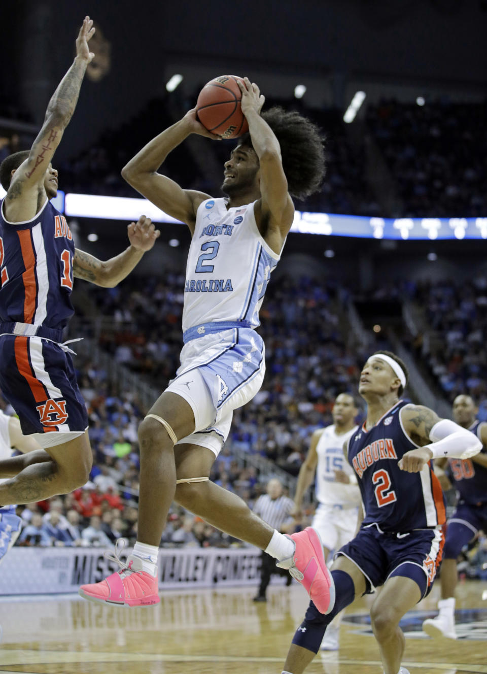 FILE - In this March 29, 2019, file photo, North Carolina's Coby White (2) heads to the basket as Auburn's J'Von McCormick, left, and Bryce Brown (2) defend during the first half of a men's NCAA tournament college basketball Midwest Regional semifinal game, in Kansas City, Mo. Ja Morant, Darius Garland and Coby White make up a clear top tier of point guards in next week’s NBA draft, though one has barely played in the past year. (AP Photo/Charlie Riedel, File)