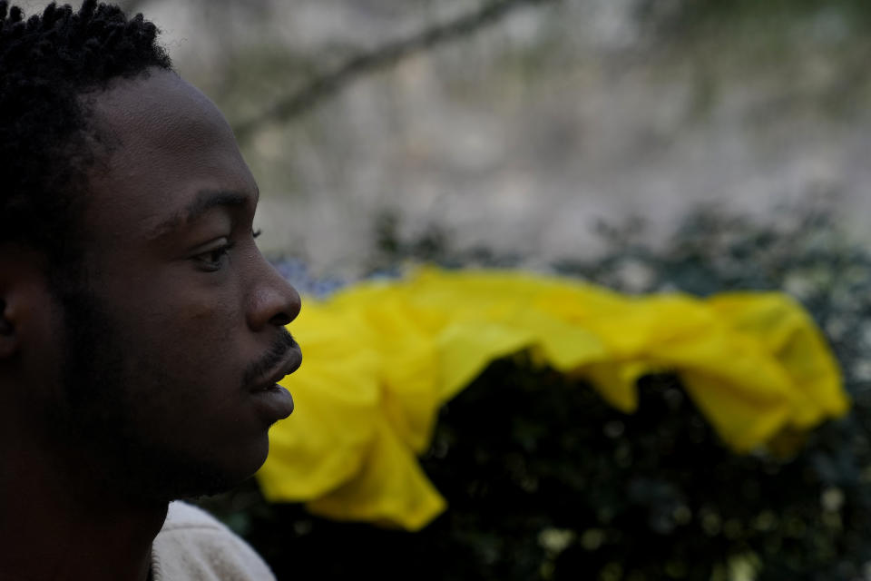 Daniel Ejuba, 20, a migrant from Cameroon, stands near a blue tent behind the House of Cooperation located inside a United Nations-controlled buffer zone cutting across Nicosia, the capital of ethnically divided Cyprus on Wednesday, Dec. 1, 2021. The Cameroonian asylum seekers crossed from the island's breakaway Turkish Cypriot north about six months ago and got stuck in the buffer zone amid a Cypriot government crackdown on migrants crossing the porous buffer zone. (AP Photo/Petros Karadjias)