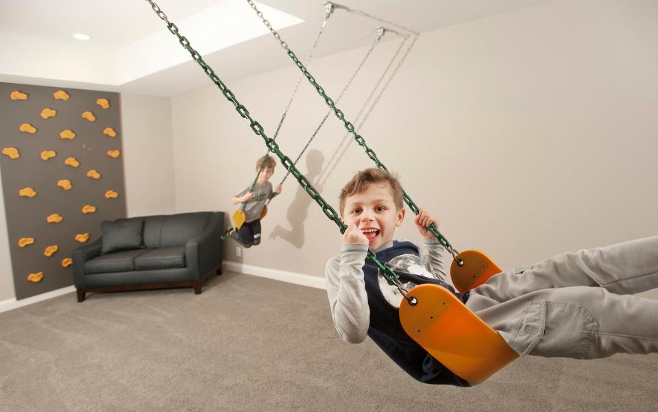 Ellis (right) and Ashur (left) Hannah play on a swing set hanging in the home's basement. At far left is a climbing wall for the boys, ages 5 and 7.01 March 2019