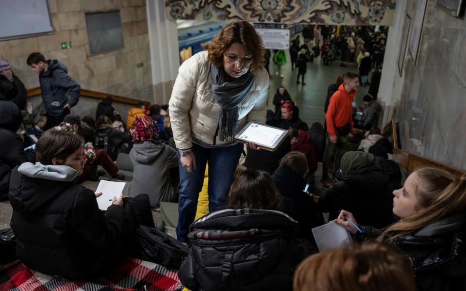 A teacher conducts a lesson for school students as they take shelter inside a metro station in Kyiv - VIACHESLAV RATYNSKYI/REUTERS
