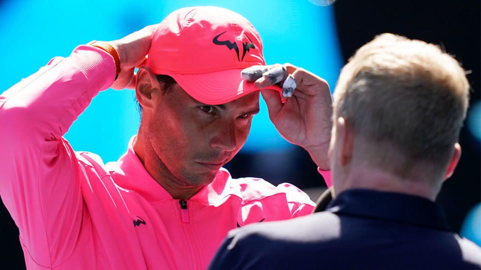 Rafael Nadal putting on his hat ahead of an interview with Jim Courier.