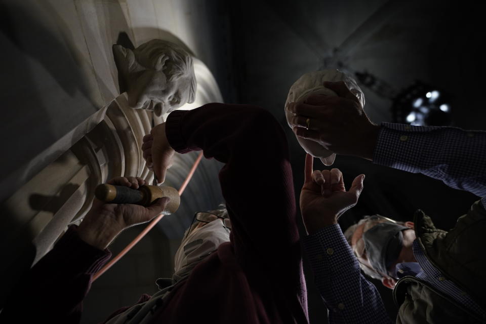 Artist Chas Fagan, right, works to fine tune his sculpture of Holocaust survivor and Nobel Peace Prize winning author Elie Wiesel with stone carver Sean Callahan in the Human Rights Porch of the Washington National Cathedral, Friday, April 16, 2021. (AP Photo/Carolyn Kaster)