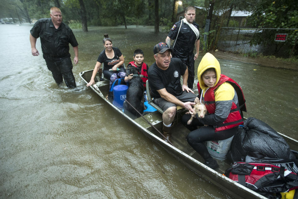 Splendora Police officers Lt. Troy Teller, left, and Cpl. Jacob Rutherford guide a boat carrying Maria, Ramiro, Jr., Ramiro and and Veronica Lopez from their flooded neighborhood inundated by rains from Tropical Depression Imelda inundates the area on Thursday, Sept. 19, 2019, in Spendora, Texas. (Brett Coomer/Houston Chronicle via AP)