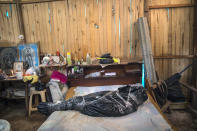 The body of Susana Cifuentes who died in her home from symptoms related to COVID-19 at the age of 71, sits on bed wrapped in a black bag and secured by tape, as a government team prepares to remove it, in the Shipibo Indigenous community of Pucallpa, in Peru’s Ucayali region, Tuesday, Sept. 1, 2020. (AP Photo/Rodrigo Abd)