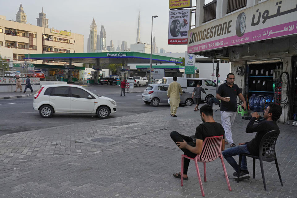 A man laughs while drinking tea as another passes holding karak in Dubai, United Arab Emirates, Wednesday, Aug. 24, 2022. Karak is the informal national drink of the United Arab Emirates, long priced at just 1 dirham, a bit less than 30 U.S. cents. But now, as supply chain shortages and Russia's war on Ukraine lead to price spikes across the world, Dubai's tea sellers are bumping up prices to 1.50 dirhams, or just over 40 cents. That's a blow to migrant workers who depend on the drink as a daily ritual offering respite and fuel. (AP Photo/Jon Gambrell)