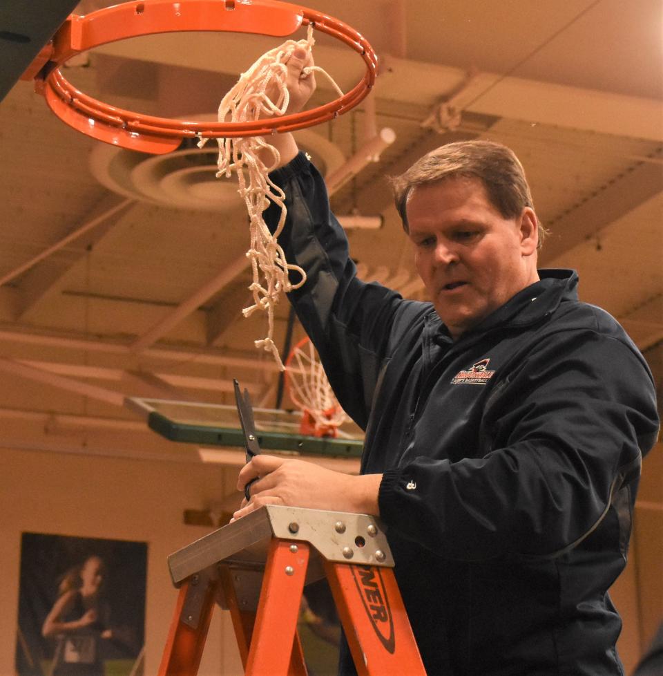 Brookdale Community College coach Paul Cisek holds up the last of the net after making his cut following the 2023 NJCAA Division III men's basketball championship game against Sandhills Community College in Herkimer. Cisek, who prviously coached at Paul Smith's College, SUNY-Potsdam and SUNY-Oswego was elected to the NJCAA Men's Basketball Coaches Association Hall of Fame in February.