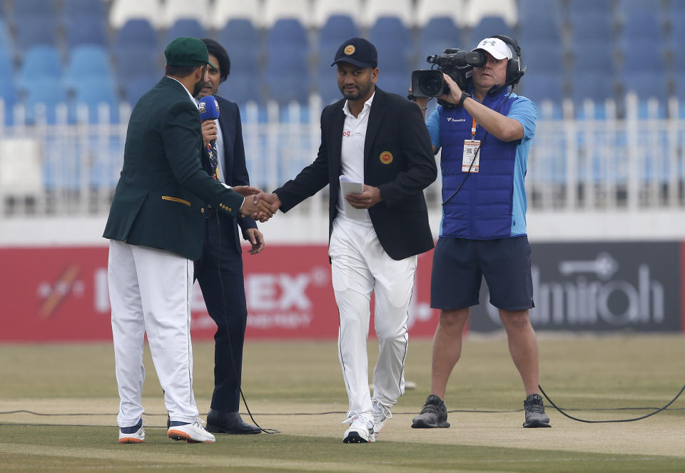 Sri Lankan skipper Dimuth Karunaratne, center, shakes hand with his Pakistani skipper Azhar Ali after won the toss for their first cricket test match in Rawalpindi, Pakistan, Wednesday, Dec. 11, 2019. (AP Photo/Anjum Naveed)