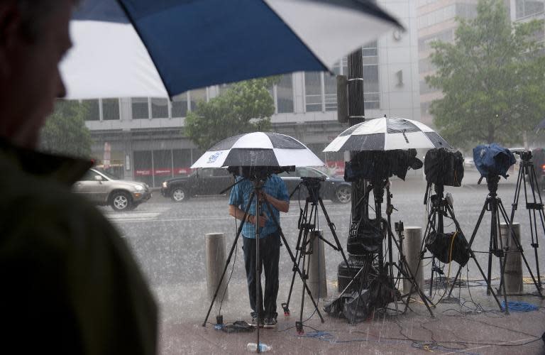 File picture shows members of the media shielding themselves from a rainstorm in Washington, DC