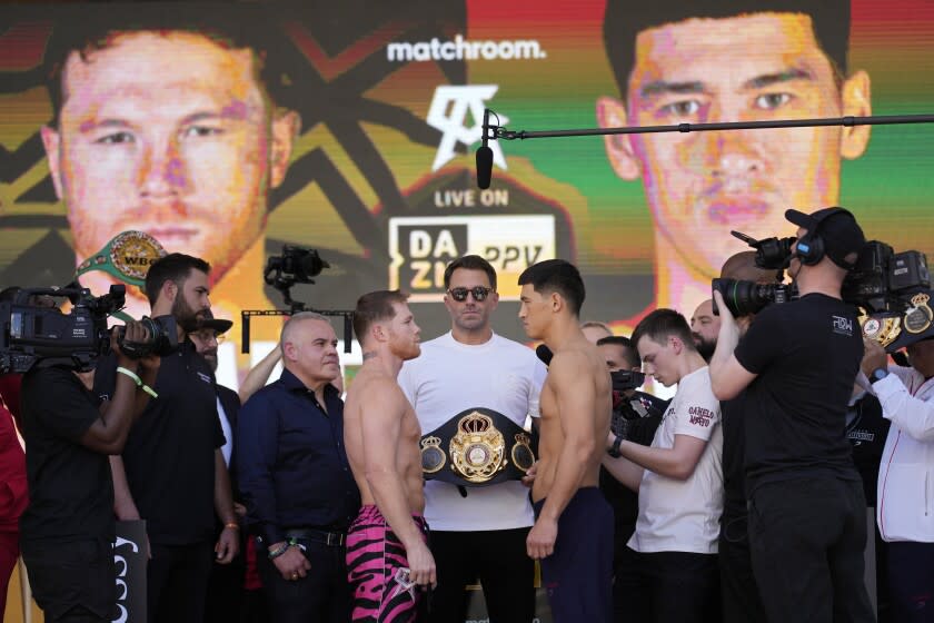 Canelo Alvarez, center left, and Dmitry Bivol, center right, pose next to promoter Eddie Hearn, center, during a ceremonial weigh-in for their Saturday boxing match, Friday, May 6, 2022, in Las Vegas. (AP Photo/John Locher)