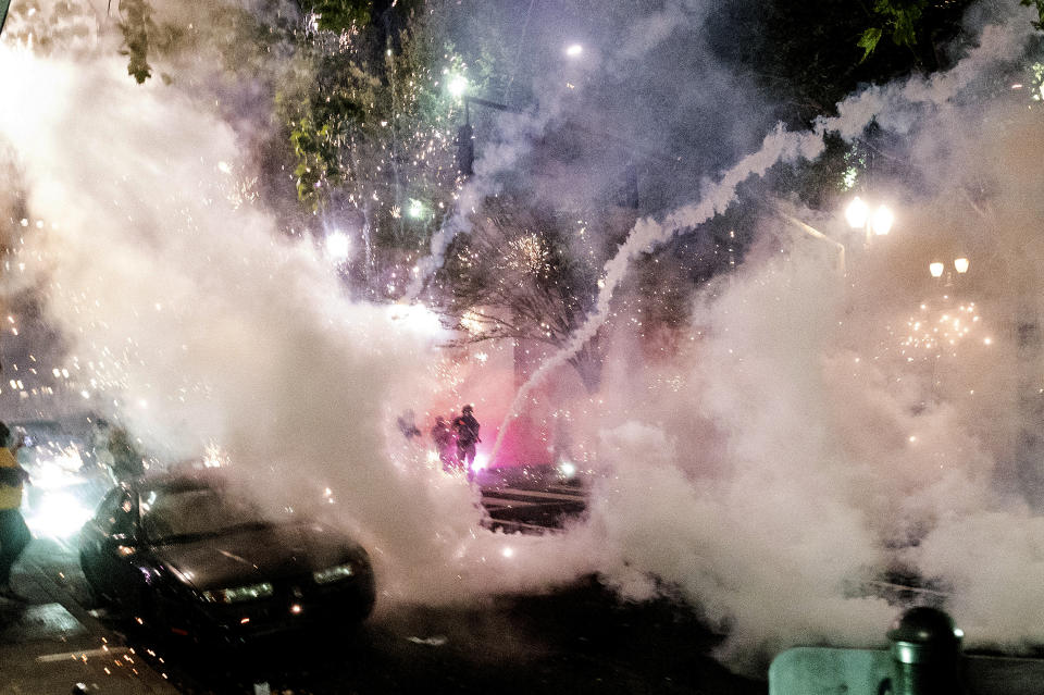 Smoke fills the sky as federal officers try to disperse Black Lives Matter protesters on Wednesday, July 22, 2020, in Portland, Ore. A federal judge is hearing arguments on Oregon's request for a restraining order against federal agents who have been sent to the state's largest city to quell protests that have spiraled into nightly clashes between authorities and demonstrators. (AP Photo/Noah Berger)