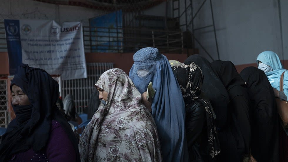 Women wait in a line to receive cash at a money distribution organized by the World Food Program (WFP) in Kabul, Afghanistan