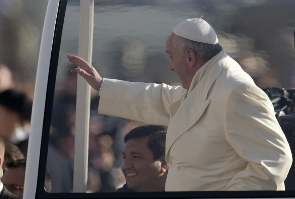 Rev. Fabian Baez, bottom left, sits behind Pope Francis on his popemobile as he arrives for his weekly general audience in St. Peter's Square at the Vatican, Wednesday, Jan. 8, 2014. Pope Francis has broken with papal protocol once again, inviting his friend Rev. Fabian Baez, a priest from Francis’ hometown in Buenos Aires, for a spin on his popemobile. (AP Photo/Alessandra Tarantino)