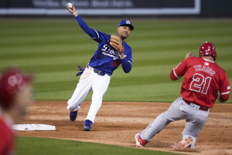 Los Angeles Dodgers second baseman Mookie Betts (50) throws to first as Los Angeles Angels' Zach Neto grounds in to a force out during the third inning of a spring training baseball game in Phoenix, Tuesday, March 5, 2024. Los Angeles Angels' Matt Thaiss (21) was out at second. (AP Photo/Ashley Landis)