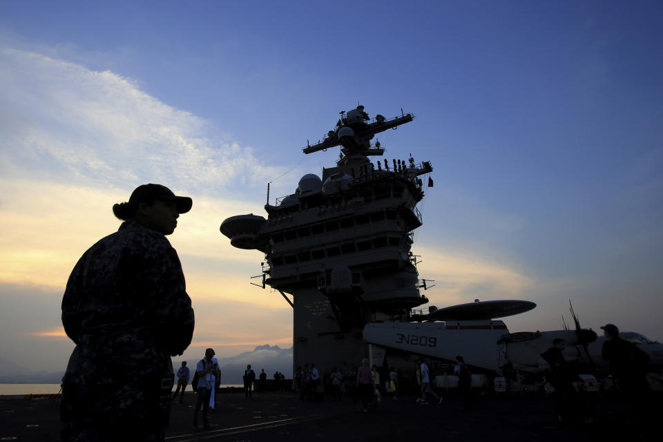 FILE - In this Monday, March 5, 2018 file photo, people stand on the deck of the USS Carl Vinson aircraft carrier as it docks in Danang bay, Vietnam. For the first time since the Vietnam War, a U.S. Navy aircraft carrier visited to a Vietnamese port, seeking to bolster both countries' efforts to stem expansionism by China in the South China Sea. (AP Photo/Hau Dinh)