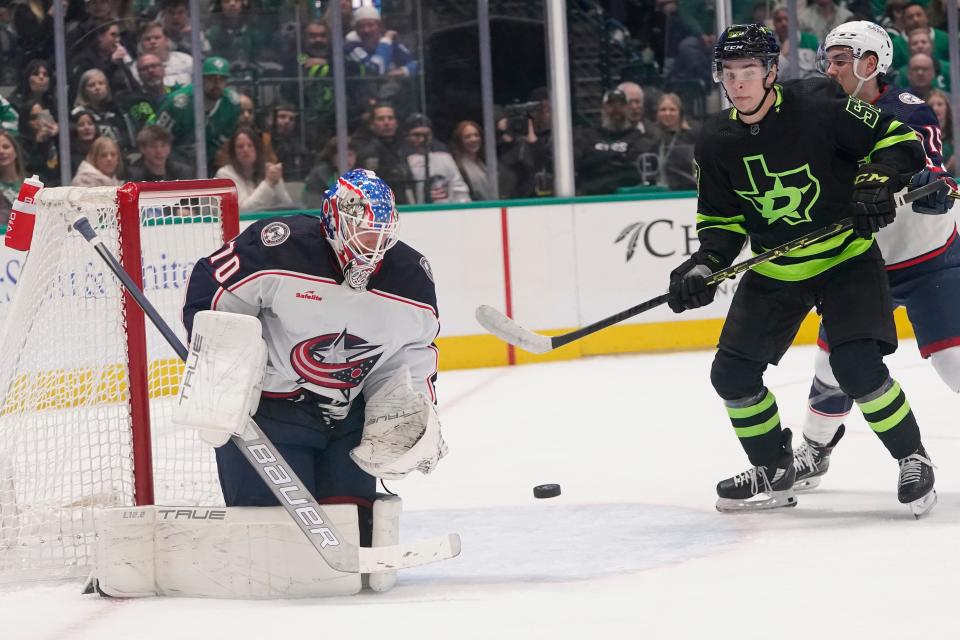 Columbus Blue Jackets goaltender Joonas Korpisalo (70) defends the goal as Dallas Stars center Wyatt Johnston (53) and Blue Jackets defenseman Gavin Bayreuther (15) look on during the first period of an NHL hockey game in Dallas, Saturday, Feb. 18, 2023. (AP Photo/LM Otero)