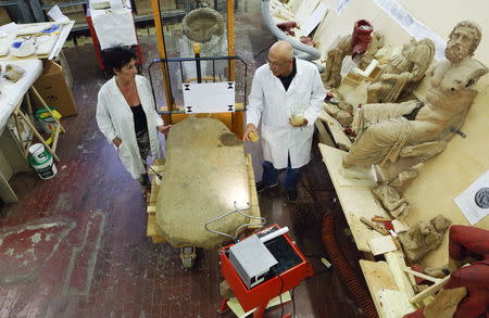 Restorer Stefano Sarri and an assistant work on an Etruscan stele at a restoration centre in Florence, Italy, April 20, 2016. REUTERS/Remo Casilli