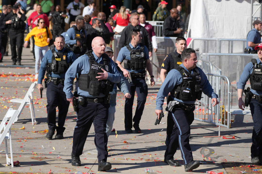 Multiple police officers, some walking with guns in hand, at the scene of the Kansas City shooting. 