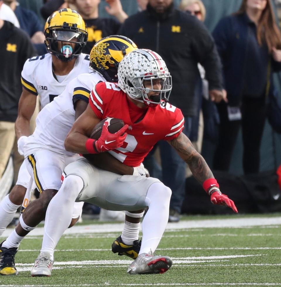 Michigan defensive back Mike Sainristil (center) tackles Ohio State Buckeyes wide receiver Emeka Egbuka (right) during the first half Nov. 26, 2022 at Ohio Stadium in Columbus.