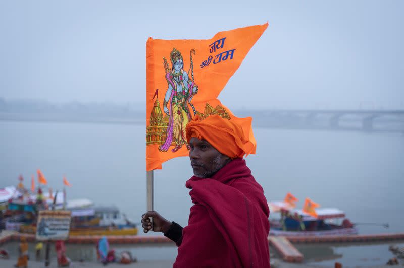 A Hindu devotee carries a flag with a picture of Lord Ram on the banks of the Sarayu River after taking a holy dip, ahead of the opening of the temple of Lord Ram in Ayodhya