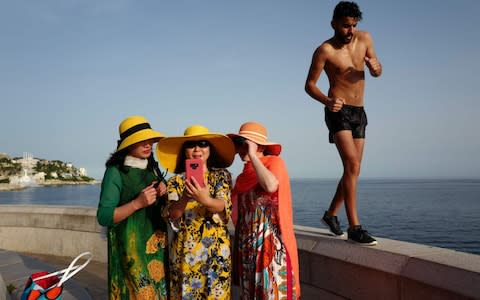 A man walks by as tourists take selfies on the French Riviera city of Nice on June 24, 2019, as temperatures soar to 33 degrees Celsius.  - Credit: &nbsp;VALERY HACHE/AFP