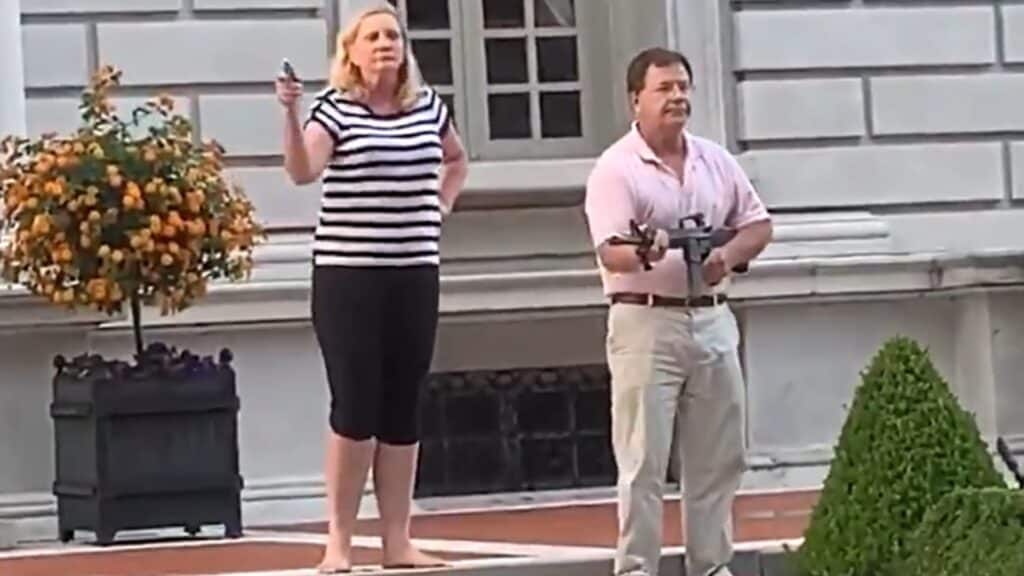 Patricia and Mark McCloskey are shown in front of their St. Louis mansion pointing guns at Black Lives Matter protesters last June. (Twitter)