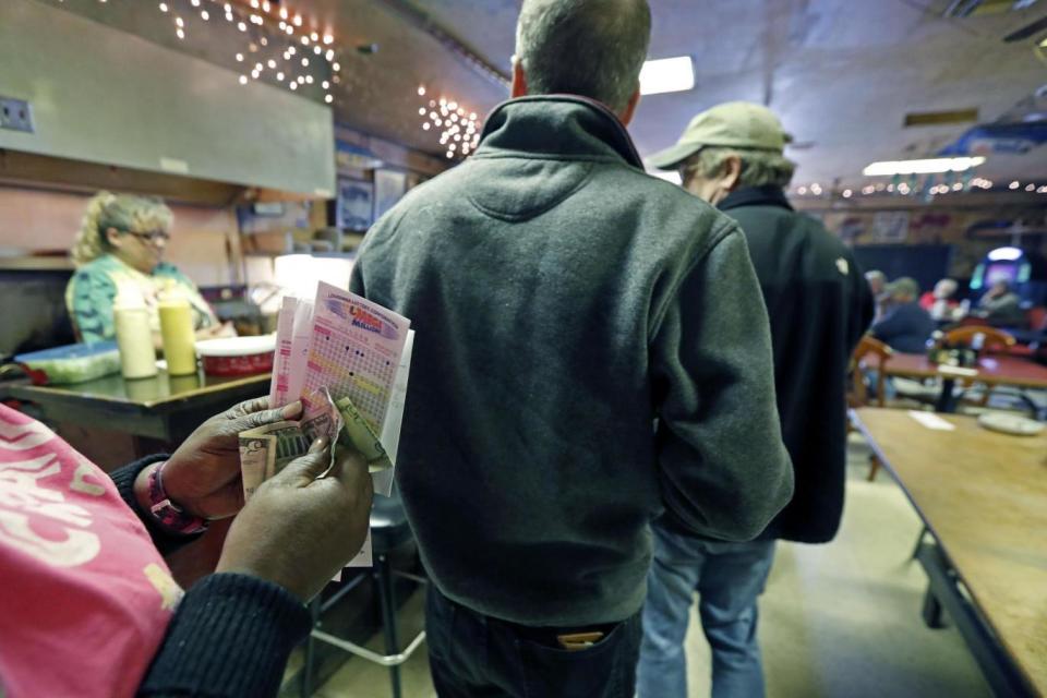 A lottery player counts her money at The World Bar and Grill, as she waits in line to purchase Mega Millions lottery tickets, in Delta (AP)