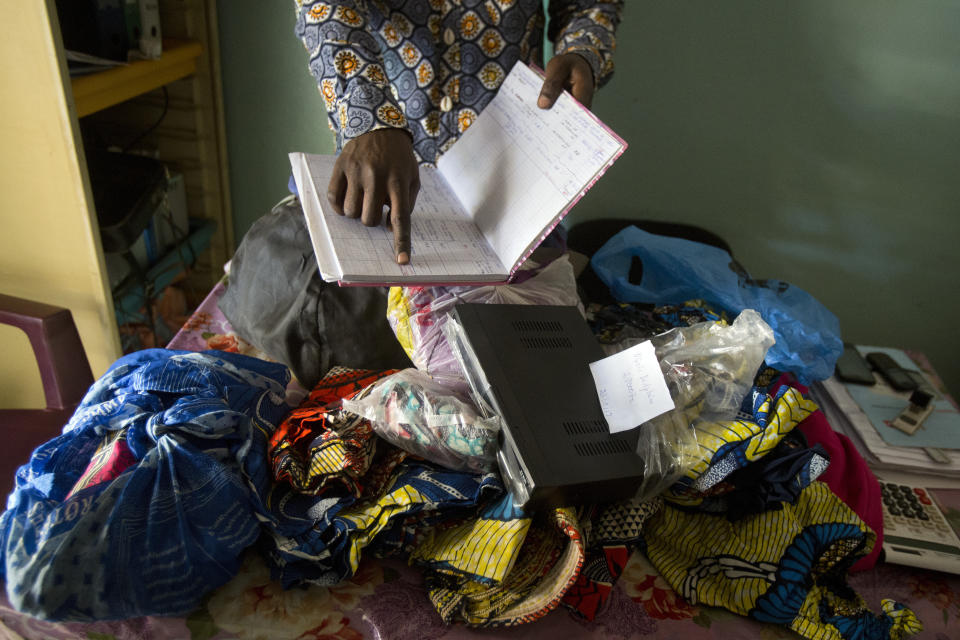 Toussain Kanyimb Nawej shows goods left as collateral by patients unable to pay their bills at the Katuba Reference Hospital in Lubumbashi, Democratic Republic of the Congo on Wednesday, Aug. 15, 2018. Hospital data obtained by The Associated Press in Congo suggest imprisonment is common in both public and private facilities, including those that receive free drugs for AIDS, malaria and reproductive health care from U.S. partners including Columbia University in New York, USAID, and the U.S. President's Emergency Plan for AIDS Relief, or PEPFAR. (AP Photo/Jerome Delay)