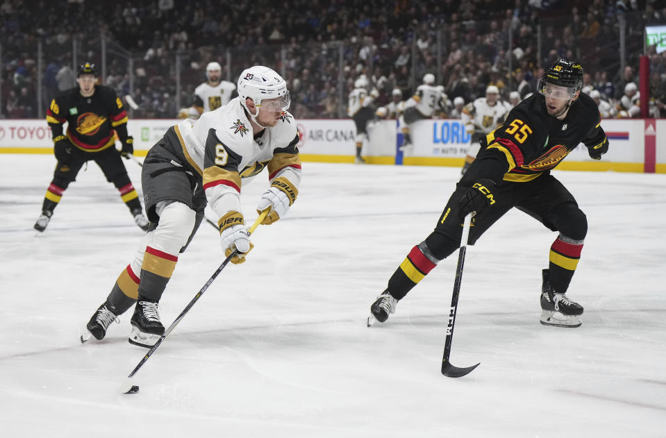 Vegas Golden Knights' Jack Eichel, left, shoots as Vancouver Canucks' Guillaume Brisebois defends during the first period of an NHL hockey game Tuesday, March 21, 2023, in Vancouver, British Columbia. (Darryl Dyck/The Canadian Press via AP)