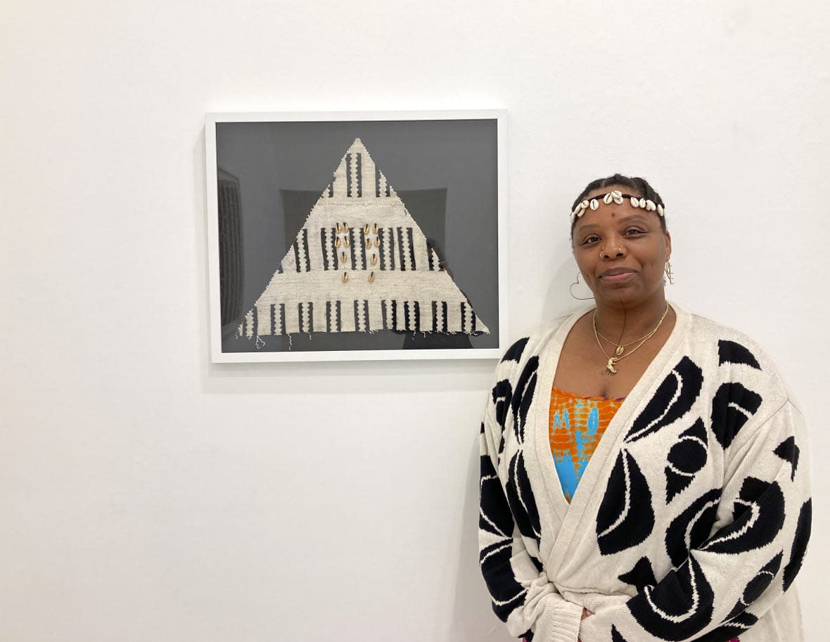 Artist and activist Patrisse Cullors stands by her artwork, made of vintage African mudcloth, yarn and cowrie shells, at the exhibit “Freedom Portals” at the Charlie James Gallery in Chinatown, Los Angeles, on March 14, 2023. (AP Photo/Jocelyn Noveck)