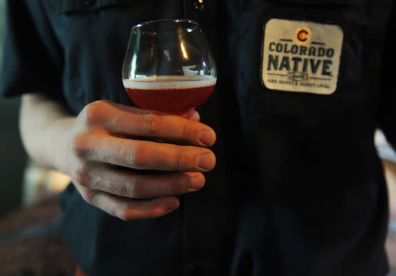 A Colorado brewer holds a glass of craft beer.