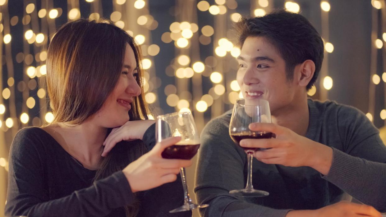 Couple toasting red wine during a romantic dinner date.