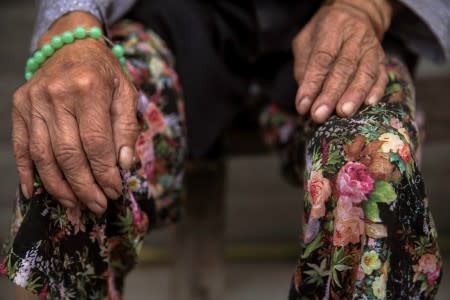 FILE PHOTO: An elderly woman passes the time outside her home in a village near Leshan in Sichuan province, China