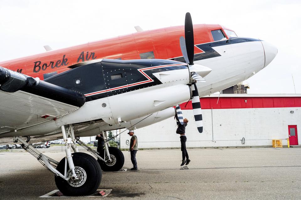 A co-pilot secures a plane that carries smokejumpers battling Canadian wildfires on Saturday, July 1, 2023, in Fort St. John, British Columbia, Canada. According to Wildfire Officer James Bergen, approximately a hundred American smokejumpers, firefighters who parachute into remote wildfires, are working with their Canadian counterparts at the Fort St. John base. (AP Photo/Noah Berger)