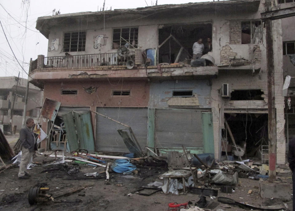 People inspect the aftermath of a car bomb explosion at a commercial street in al-Ameen district in southeastern Baghdad, Iraq, Sunday, March 16, 2014. A series of car bomb attacks targeting commercial areas and a restaurant killed and wound scores of people, Saturday in Iraq's capital, Baghdad, authorities said. (AP Photo/Khalid Mohammed)