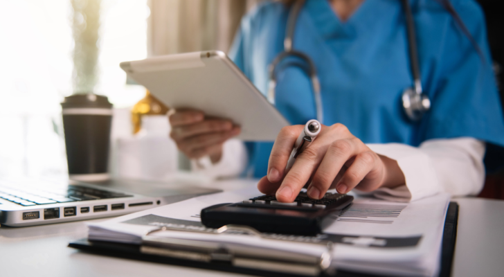 Doctor or physician calculating a patients medical bills at a desk. Medical bills, health costs, health expenses.