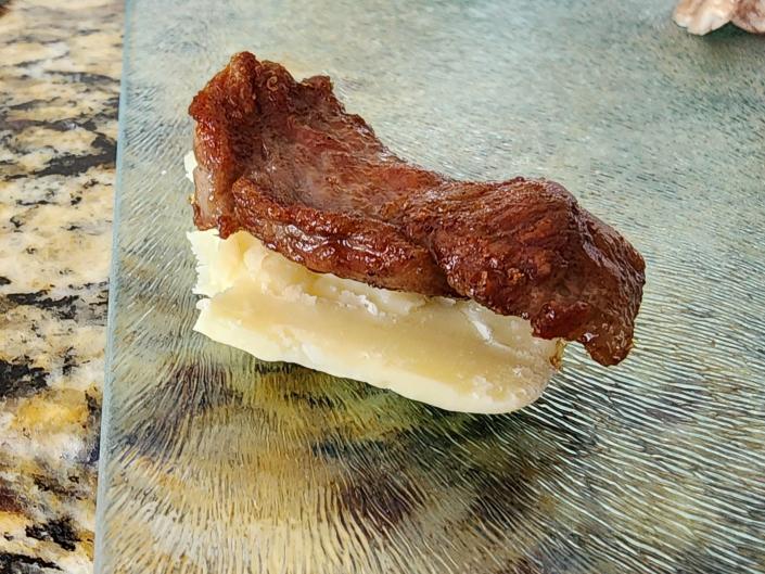 a piece of cooked wagyu steak on a shard of white cheddar cheese