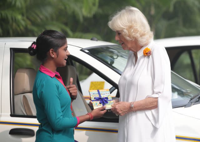 Camilla is presented with the book Lady Driver by taxi driver Poonam from Women on Wheels