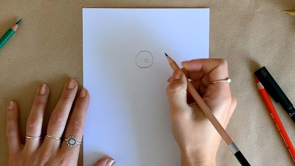 a person drawing a circle for santa's head on white paper