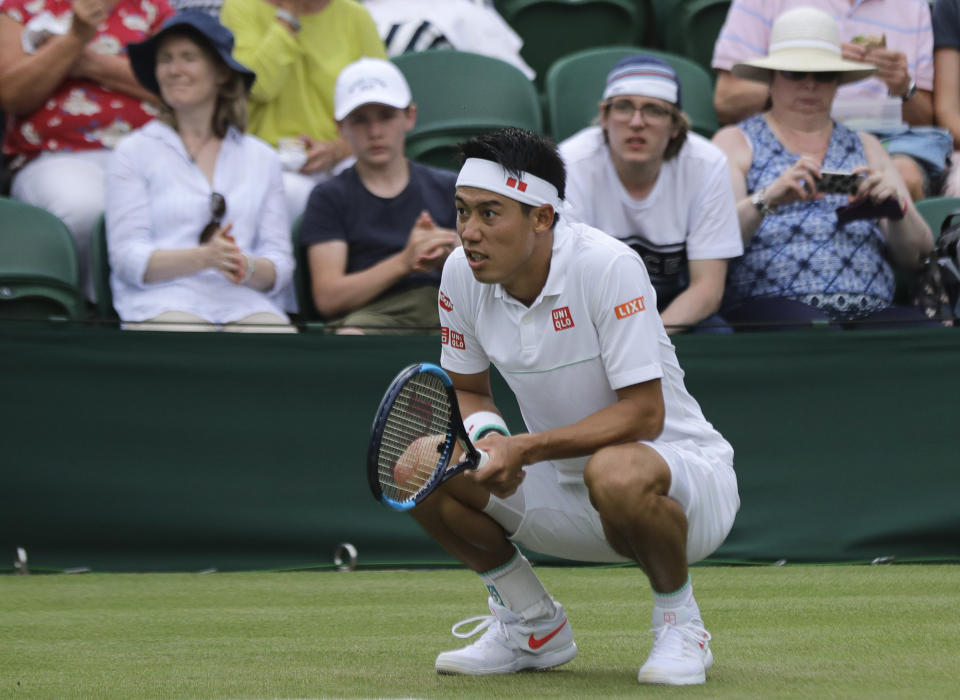 Japan's Kei Nishikori crouches after returning the ball to Kazakhstan's Mikhail Kukushkin in a men's singles match during day seven of the Wimbledon Tennis Championships in London, Monday, July 8, 2019. (AP Photo/Ben Curtis)