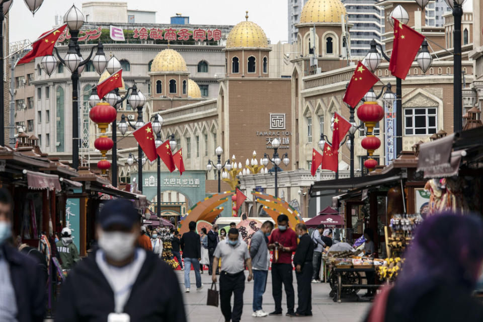 Pedestrians walk past stalls at the Xinjiang International Grand Bazaar in Urumqi, Xinjiang province.