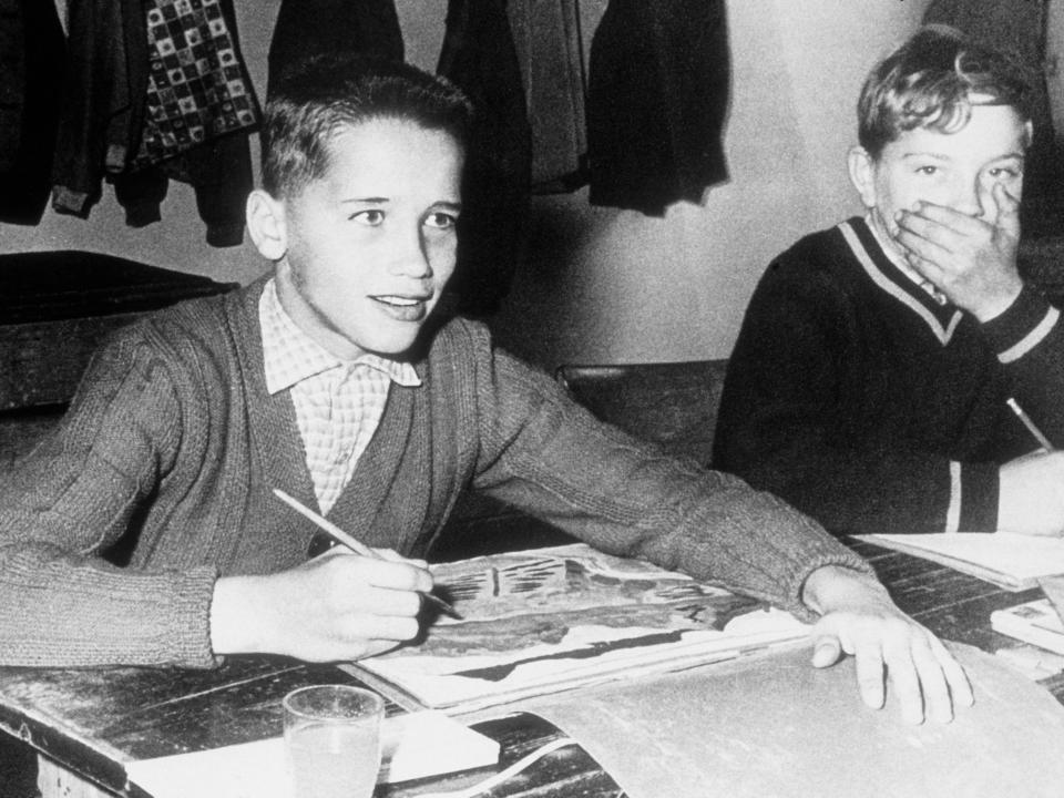 Arnold Schwarzenegger poses for a photo in a classroom when he was 11 years old.