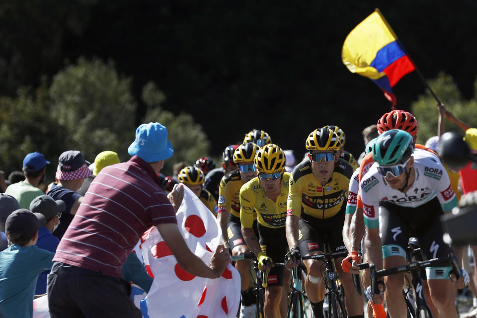 Spectators cheer the pack with Slovenia's Primoz Roglic, wearing the yellow jersey of the overall leader during the 14th stage of the Tour de France cycling race over 194 kilometers (120,5 miles) with start in Clermont-Ferrand and finish in Lyon, France, Saturday, Sept. 12, 2020. (AP Photo/Thibault Camus)