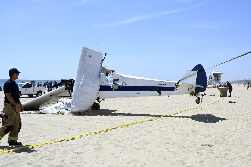 Investigators look at a small plane that was pulled from the water after it crashed into the ocean in Huntington Beach, Calif., Friday, July 22, 2022. The plane towing a banner crashed in the ocean Friday during a lifeguard competition that turned into a real-life rescue along the popular beach. (Brittany Murray/The Orange County Register via AP)