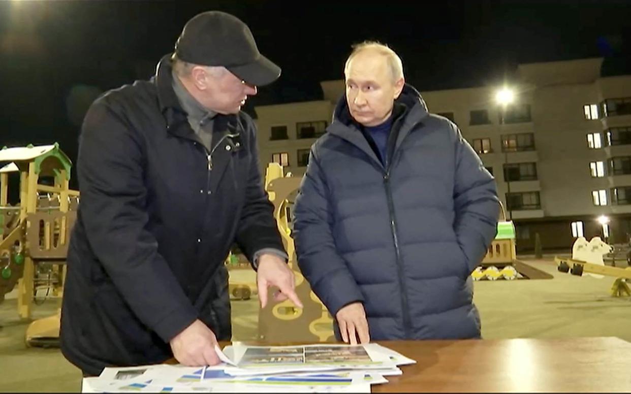 Russian President Vladimir Putin listens to Deputy Prime Minister Marat Khusnullin, who heads construction and regional development, as he visits Mariupol, Russian-controlled Ukraine