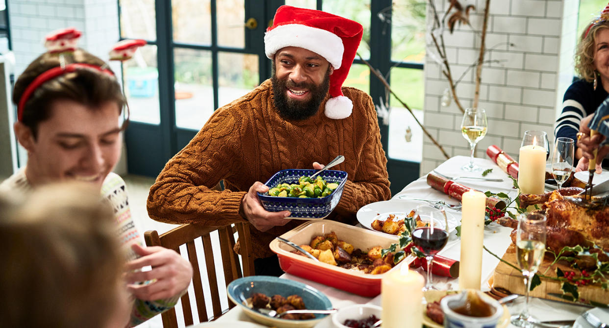 Friends and family sitting round a table enjoying Christmas dinner. (Getty Images)