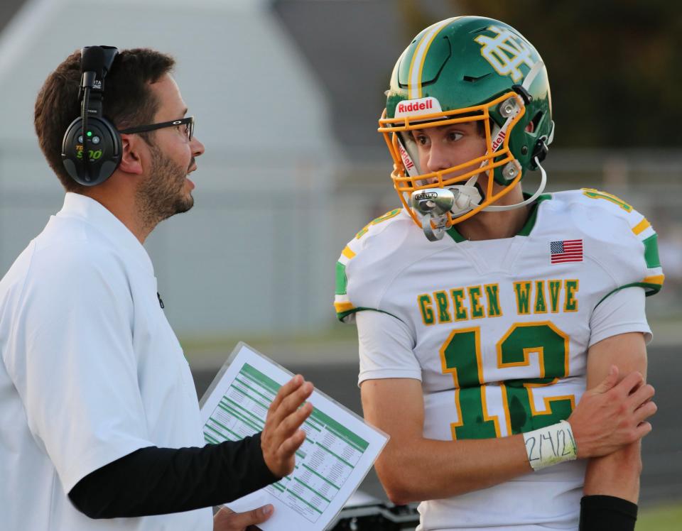 Newark Catholic sophomore quarterback Miller Hutchison confers with assistant coach Tate Borlik on the sidelines during the 27-9 win at Fort Loramie.