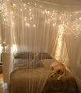 <p>Create a magical cocoon around your bed with a gauzy and glittering canopy. Simply hang sheer drapery panels on wire rope threaded through eye hooks in the ceiling and accent with strings of cascading holiday lights.</p><p><a rel="nofollow noopener" href="http://www.oliveandlove.com/2011/08/ceiling-mounted-bed-canopy-2.html" target="_blank" data-ylk="slk:Get the tutorial from Olive and Love;elm:context_link;itc:0;sec:content-canvas" class="link ">Get the tutorial from Olive and Love</a></p>