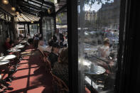 People sit on the Cafe de Flore terrace in Paris, Tuesday, June 2, 2020. Local Parisians are savoring their cafe au lait and croissants at the Left Bank's famed Cafe de Flore, or on the cobbled streets of the ancient Le Marais for the first time in almost three months. As virus confinement measures were relaxed Tuesday, cafes around France were allowed to reopen. (AP Photo/Christophe Ena)