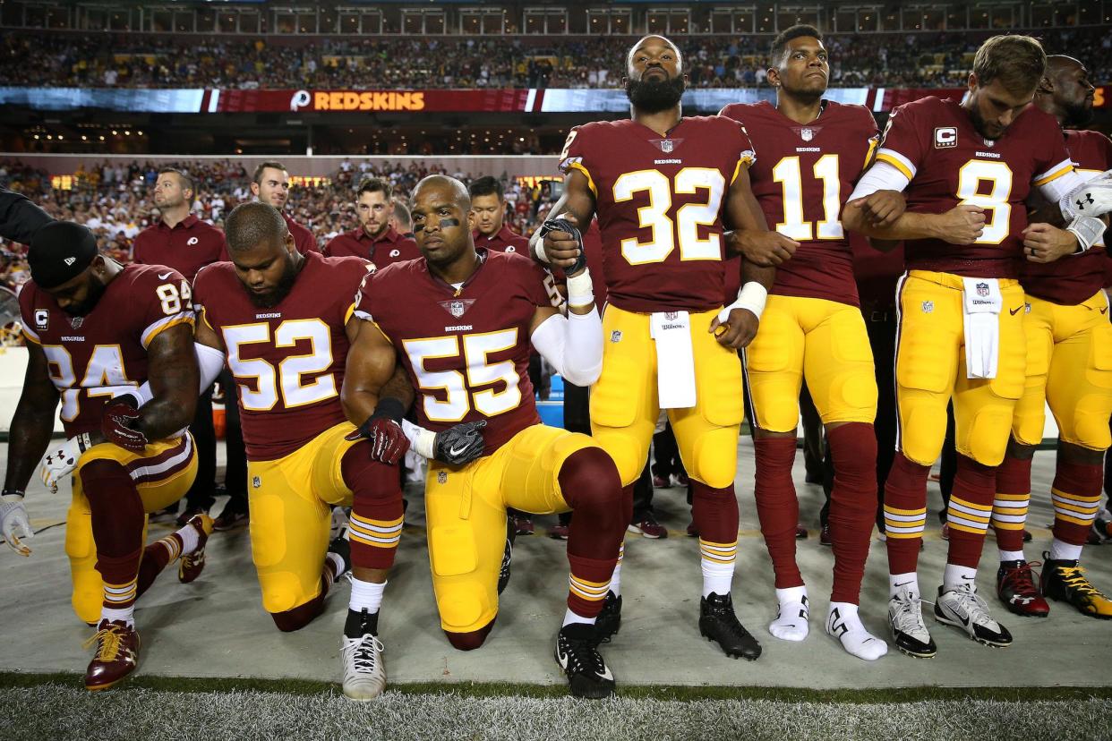 Washington Redskins platers hold hands as they stand and kneel in unison during the national anthem on September 24, 2017 in Landover, Maryland: Patrick Smith/Getty Images