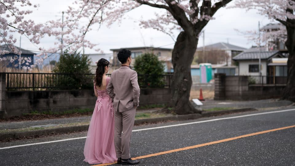A couple poses for a wedding photograph near blossoming cherry trees in the Yonomori area of Fukushima, Japan, on April 2, 2023. - Tomohiro Ohsumi/Getty Images